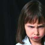 pretty little brunette girl on black background frowning