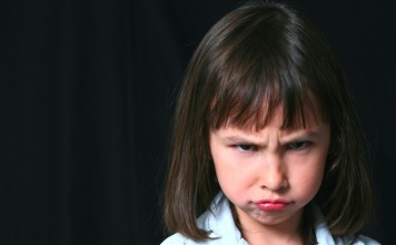 pretty little brunette girl on black background frowning