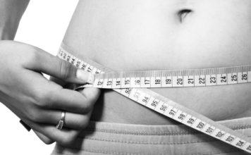 gray scale women's belly with measuring tape wrapped around it