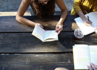 three people study at a wooden picnic table