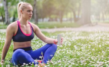 Woman sitting in grass holding an energy drink