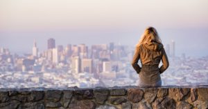 Woman sitting on a rock wall looking over the city
