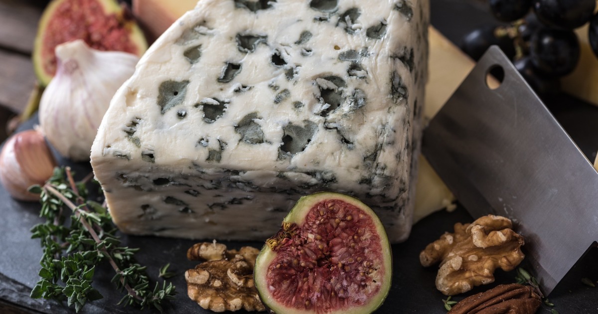 large cheese wedge with nuts and a fig