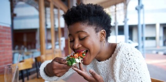 black woman taking a bite of vegan food