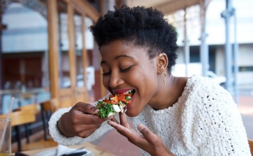 black woman taking a bite of vegan food