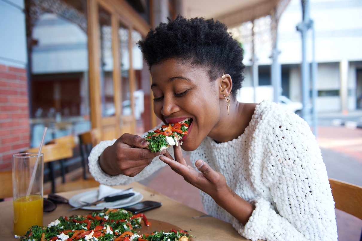 black woman taking a bite of vegan food
