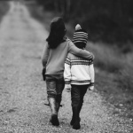 black and white image of a boy and girl walking down a dirt road