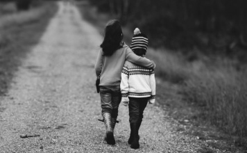 black and white image of a boy and girl walking down a dirt road
