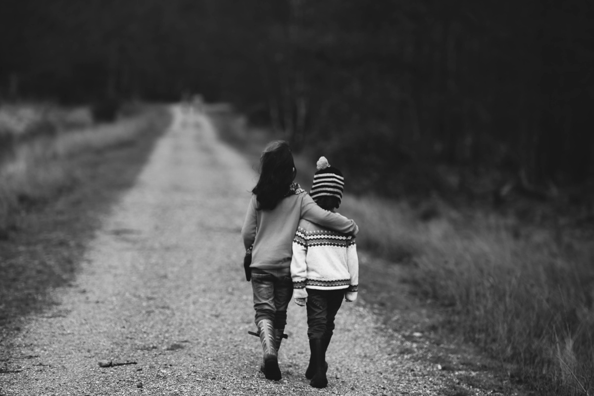 black and white image of a boy and girl walking down a dirt road