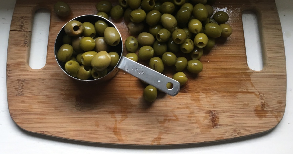 pitted green olives on a wood board