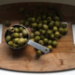 pitted green olives on a wood board