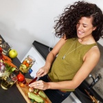 happy woman cutting produce on a cutting board