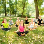 group of young people doing yoga in park
