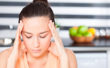 Have a Headache? Listen to This! Stressed young woman in kitchen