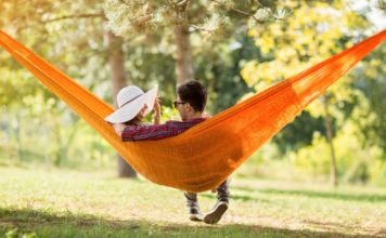 Young man and woman on hammock in green nature from back