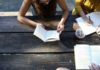 three people study at a wooden picnic table