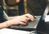 person sitting and typing on a laptop computer