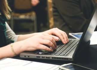 person sitting and typing on a laptop computer