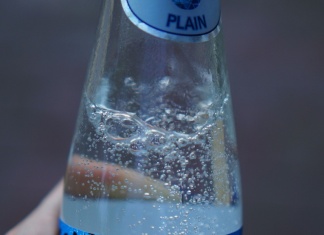It’s Time to Ditch Artificial Sweeteners for Good—Here’s Why hand holding a bottle of sparkling water