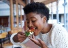 black woman taking a bite of vegan food