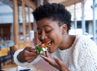 The Real Secret to Living to 100? Plants, According to the Largest Diet Study Yet black woman taking a bite of vegan food
