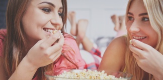 two friends, talking, smiling, and eating popcorn
