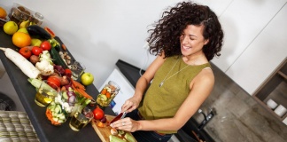 happy woman cutting produce on a cutting board