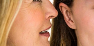 Woman whispering into another woman's ear